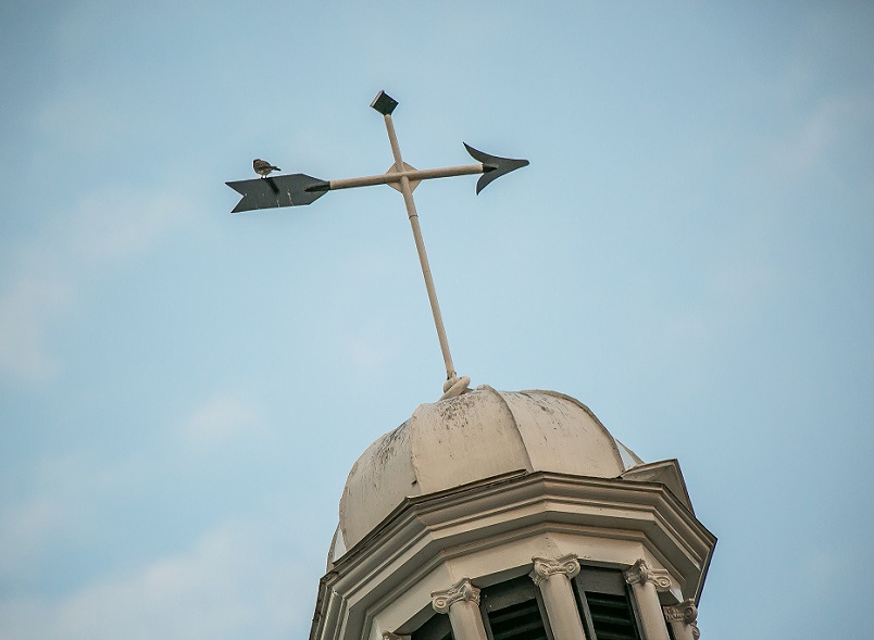 The Top of a Court House Building With a Wind Pointer